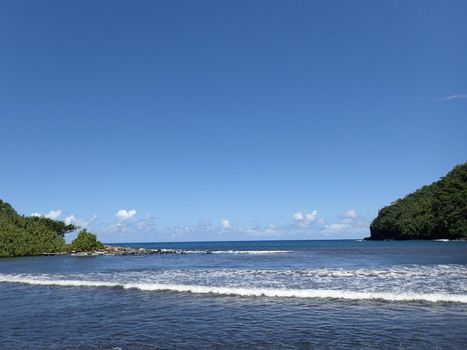 Waves lap on black sand beach at Honomanu Park on the Road to Hana, Maui, Hawaii