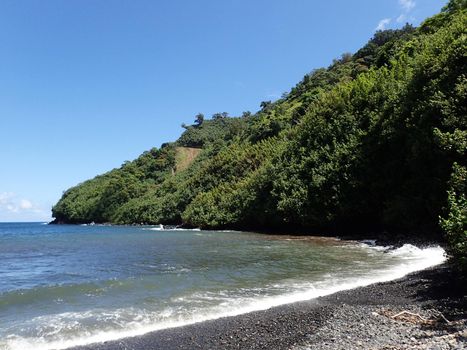 Waves lap on black sand beach at Honomanu Park on the Road to Hana, Maui, Hawaii.