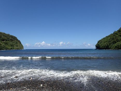 Waves lap on black sand beach at Honomanu Park on the Road to Hana, Maui, Hawaii