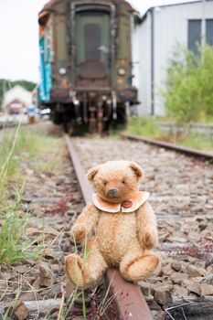 a cute brown teddy bear sits alone on empty mini-rails and looks into the distance, do-it-yourself toy. High quality photo