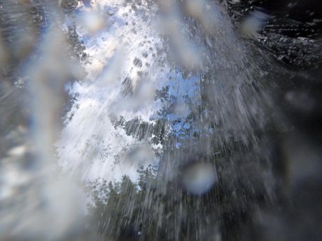 Waterfall pours downwards with trees and sky above.  Great Background or abstraction.