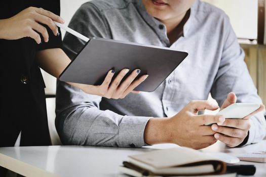 Focus on men using smartphones While the secretary uses a tablet to talk about the company's profitability budget this quarter