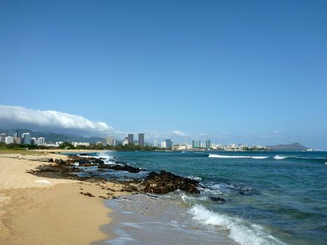 Sand Island beach off the coast of Oahu, Hawaii.  Featuring crashing waves and Downtown Honolulu, Waikiki in the background.