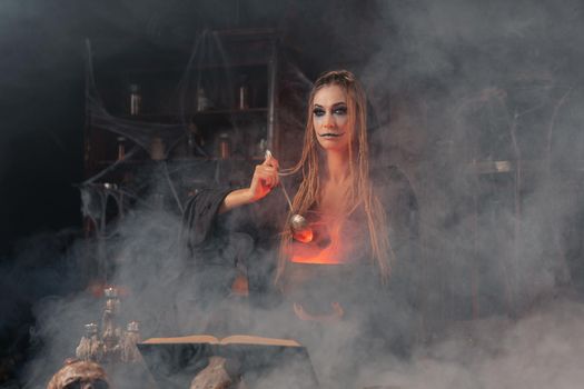 Halloween, witch use magic book and cauldron prepare poison or love potion. Black magic occult female wizard in dark room