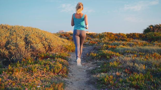 Runner Woman Running Sunny Path Road near Ocean. Sportswoman Morning Jogging Training. Healthy Lifestyle. Mindful Run. Caucasian female jogger. Healthy lifestyle Back view
