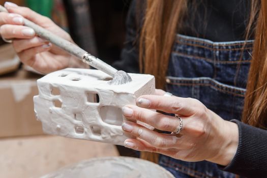 A master ceramist holds a clay product in his hands. Making a ceramic candle holder from clay. The process of coating the candlestick with glaze. Close-up.