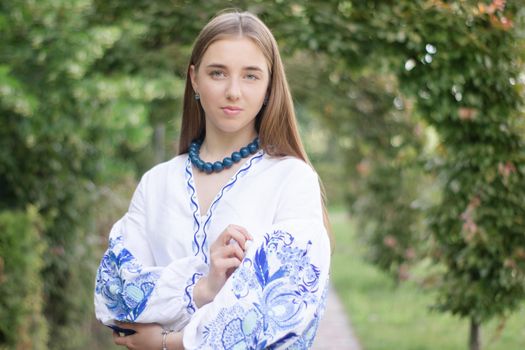 ukrainian blonde girl in national blue dress - embroidered shirt. young woman patriot. outdoors photo of charming female.