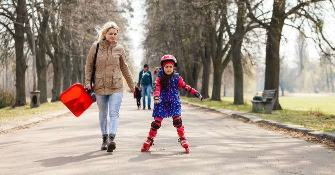 Caucasian woman teaches her daughter to skate on roller skates.