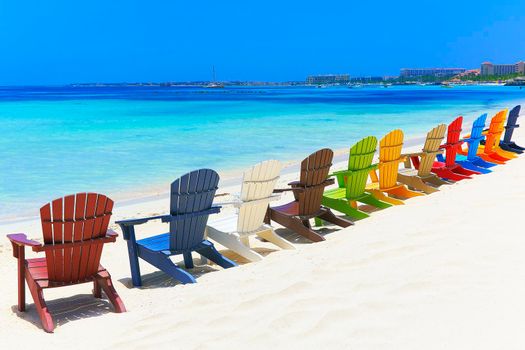 Colorful adirondack chairs on idyllic palm beach in Aruba, Caribbean sea