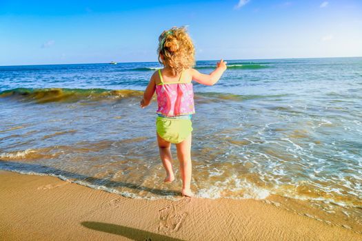 My little daughter jumping happy on the beach in idyllic Punta Cana, Dominican Republic.