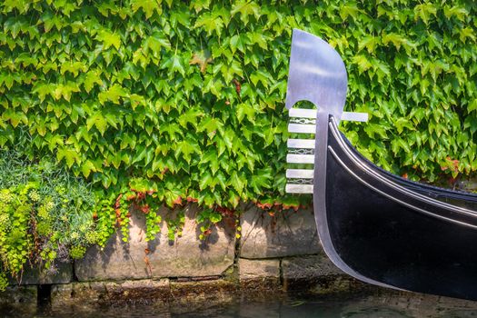Close-up of one gondola anchored in front of a green wall in Venice, Italy.