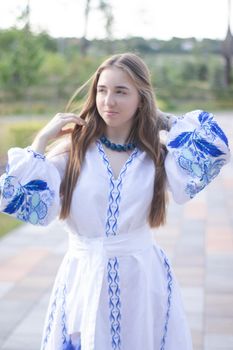 ukrainian blonde girl in national blue dress - embroidered shirt. young woman patriot. outdoors photo of charming female.