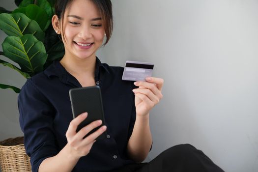 Online payment, Young Women's hands holding credit card and using smartphone for online shopping at home.