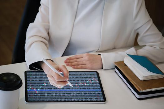 Business woman using tablet to trade charts to find buy and sell points for her port