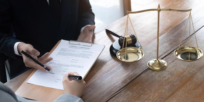 Business woman and lawyers discussing contract papers with brass scale on wooden desk in office. Law, legal services, advice, Justice concept..