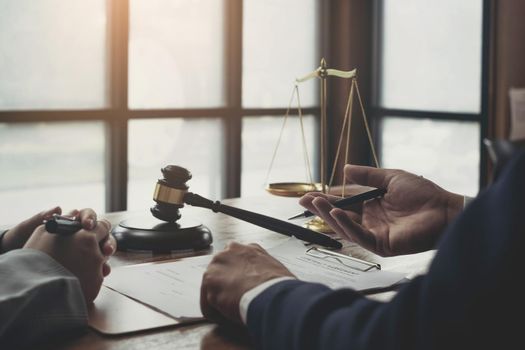 Business woman and lawyers discussing contract papers with brass scale on wooden desk in office. Law, legal services, advice, Justice concept.