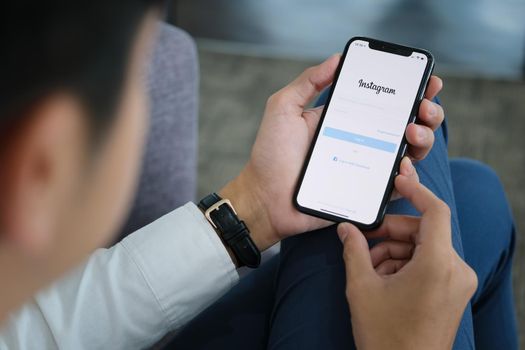 CHIANG MAI, THAILAND - April 06, 2021 : A man hand holding iphone with login screen of instagram application. Instagram is largest and most popular photograph social networking.