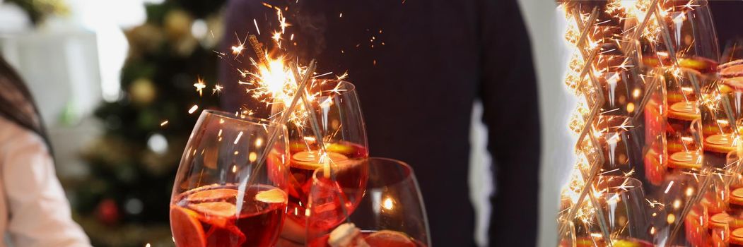 Close-up of people doing clink with glasses filled with champagne beverage. Fire sparkles, celebrate new year in company. Party, nightlife, holiday concept