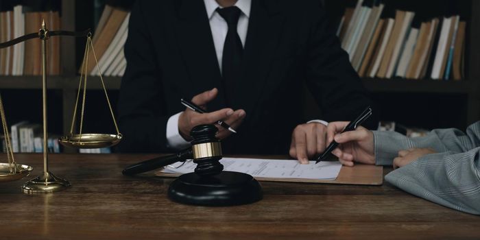 Business woman and lawyers discussing contract papers with brass scale on wooden desk in office. Law, legal services, advice, Justice concept..