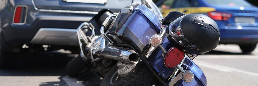 Close-up of traffic accident between electric bicycle and car, motorbike fell on asphalt. Bike crashed into automobile. Highway, road accident concept