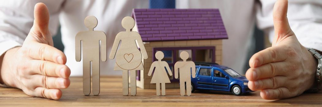 Close-up of business agent propose to take care of health, car and house insurance policy. Miniature model of family, building and auto. Protection concept