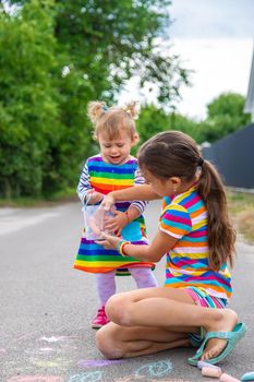 The child draws with chalk on the pavement. Selective focus. Kid.