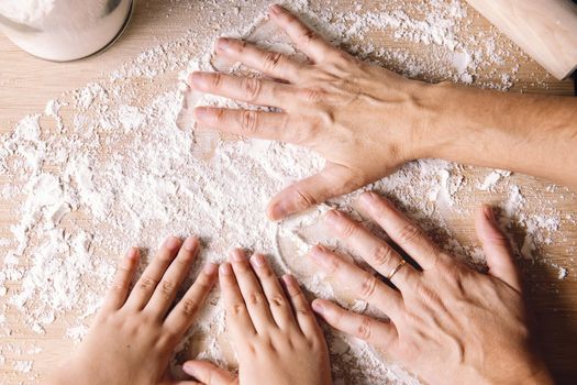 mother and daughter hands putting flour on the kitchen table, concept of healthy food at home