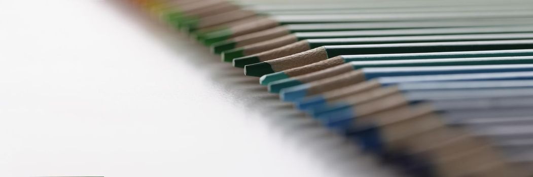 Close-up of set of pencils perfectly arranged in line on white surface for childs art. Macro shot of crayons ready for drawing. Creativity, vision concept