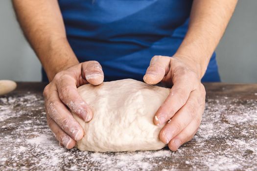 hands of an unrecognizable woman making bread dough on a wooden table, concept of healthy food at home