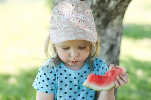 cute little girl eating watermelon outdoors in summertime. Child and watermelon in summer
