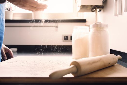 unrecognizable man hands sprinkling flour on the kitchen tabletop, concept of healthy food at home
