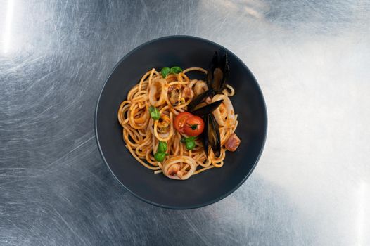 Seafood Pasta with mussels with basil and tomato in black plate
