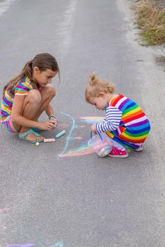 The child draws with chalk on the pavement. Selective focus. Kid.