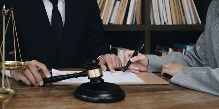 Business woman and lawyers discussing contract papers with brass scale on wooden desk in office. Law, legal services, advice, Justice concept..