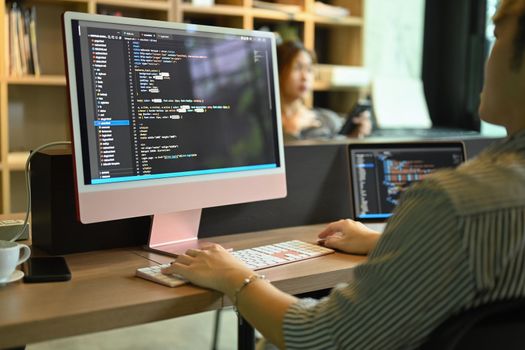 Cropped view male software developer checking mistakes in programming code on computer screen.