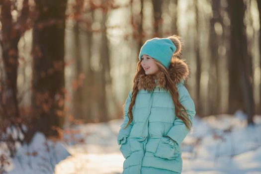 little girl in a winter forest and turquoise-colored clothes