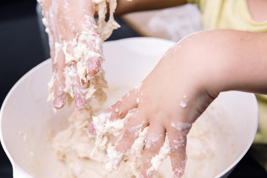child hands smeared with homemade bread dough, concept of healthy eating at home