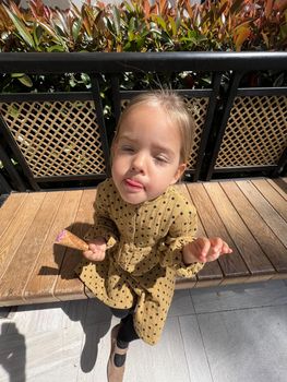 Little girl sits licking her lips with an ice cream cone in her hand. High quality photo