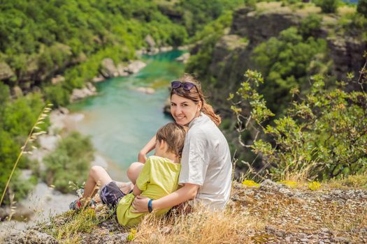 Mother and son tourists on background of purest waters of the turquoise color of the river Moraca flowing among the canyons. Travel around Montenegro concept.