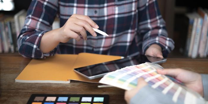 Two artists working on tablet, colour paper tone on workspace at the office.