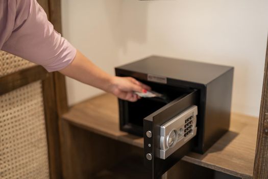 Hand putting password in the safety money box in hotel room