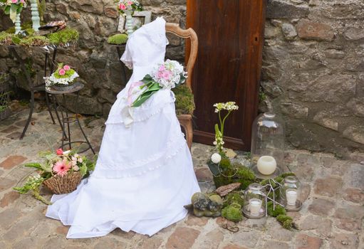 Vintage wedding dress on a wooden chair against the backdrop of a stone wall