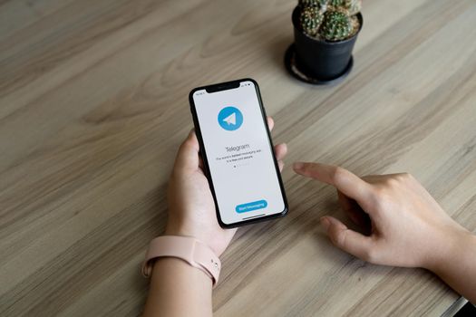 CHIANG MAI, THAILAND, JUL 12, 2022 : Woman hand holding iPhone X with social networking service Telegram on the screen. iPhone 10 was created and developed by the Apple inc