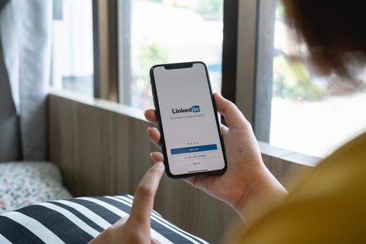 CHIANG MAI, THAILAND, JUL 12, 2022 : A women holds Apple iPhone Xs with LinkedIn application on the screen.LinkedIn is a photo-sharing app for smartphones