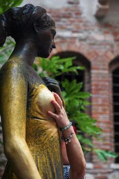 Woman rubs Juliet's chest for good luck in her garden in Verona
