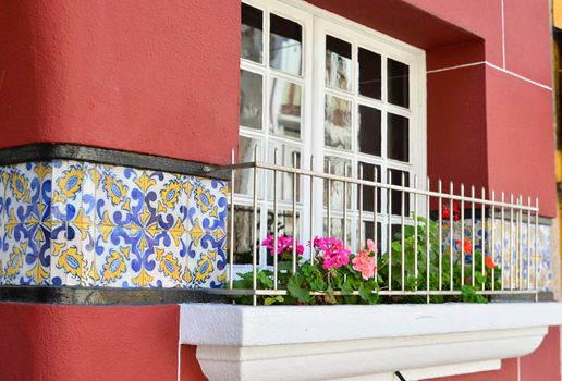 Window with a geranium on the windowsill and tiles azulejo in Portugal