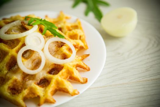 fried potato cheese vegetable waffles with bacon and onions in a plate, on a wooden table.