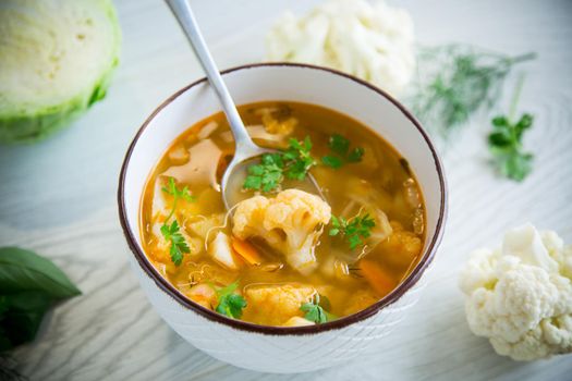 vegetable summer soup with cauliflower in a bowl on a light wooden table
