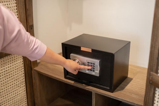 Woman opening modern safe indoors