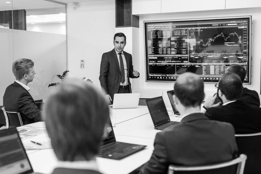 Business man making a presentation at office. Business executive delivering a presentation to his colleagues during meeting or in-house business training. Black and white image.